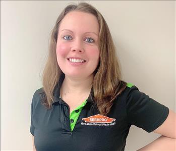 Woman with brown hair smiling for employee photo with black and green Servpro polo on. 