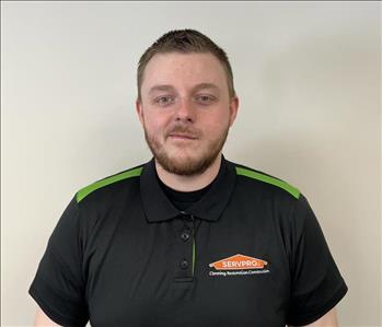 Man with short dark hair and beard smiling for employee photo with black and green Servpro polo on. 